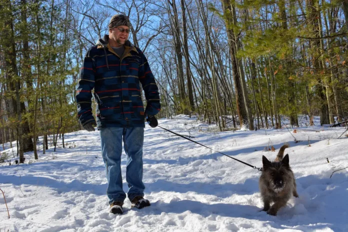 man walking his dog on snowy trail