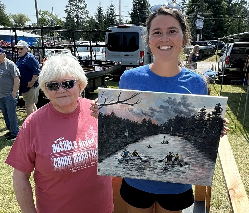 Jane Croze presents a painting to Lexi Cherven