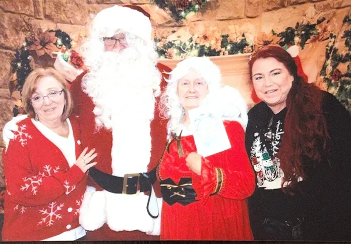 richland fire pic 1 Coordinator Peggy Mashke and volunteer Deanna Roberts stop for a moment to pose for a picture with Santa and Mrs. Claus at the Richland Logan Firehouse Christmas event.