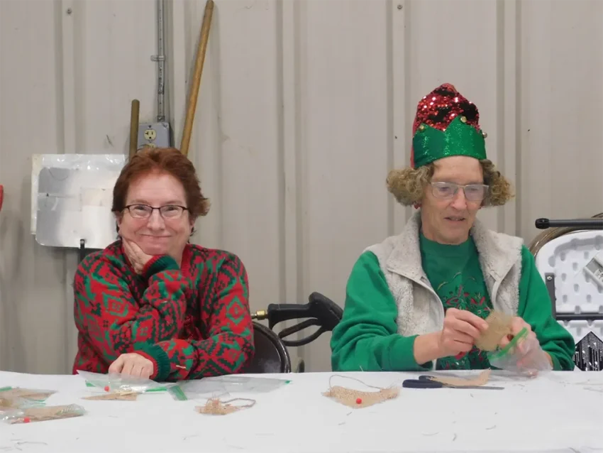 Colleen Boyd, librarian for the Ogemaw East branch district library, and Rhoda Clark, help children make reindeer Christmas tree decorations.