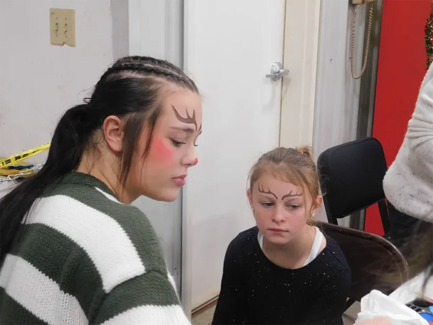 Skyler Friday getting a reindeer painted on her face by Gabby Clark.
