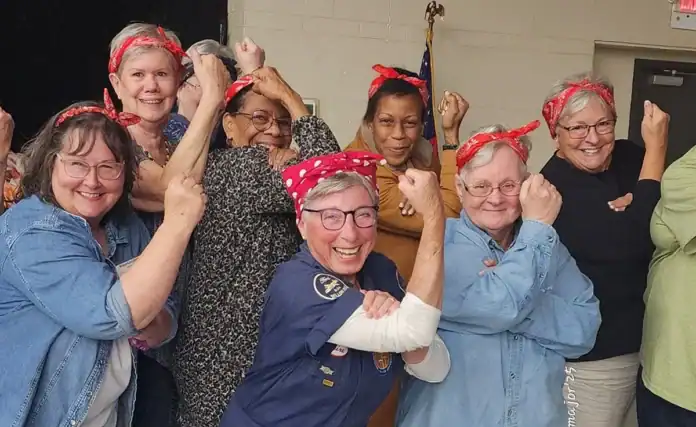 Claire Kichin Dahl, aka “Rosie the Riveter”, strikes her iconic pose with women who attended her presentation.