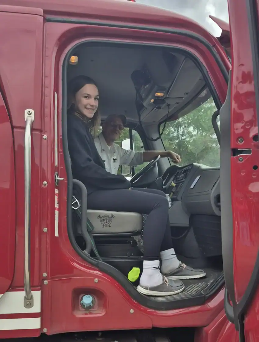 Volunteer firefighter Mike Ross driving Sylvia Discola around a fire truck.