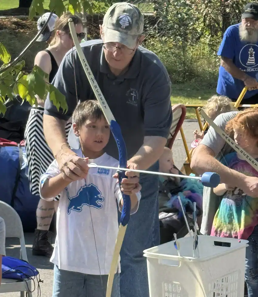 Mike Ritchie shows Jacob Ford the basics of archery.