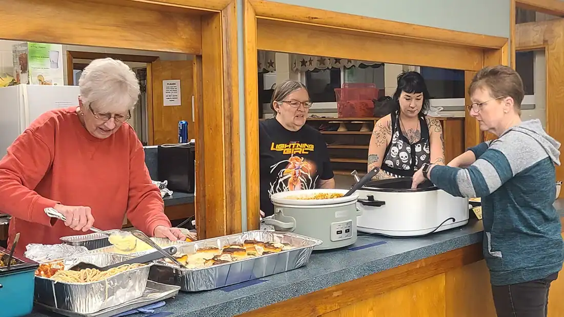 Group of women preparing meal items for community potluck
